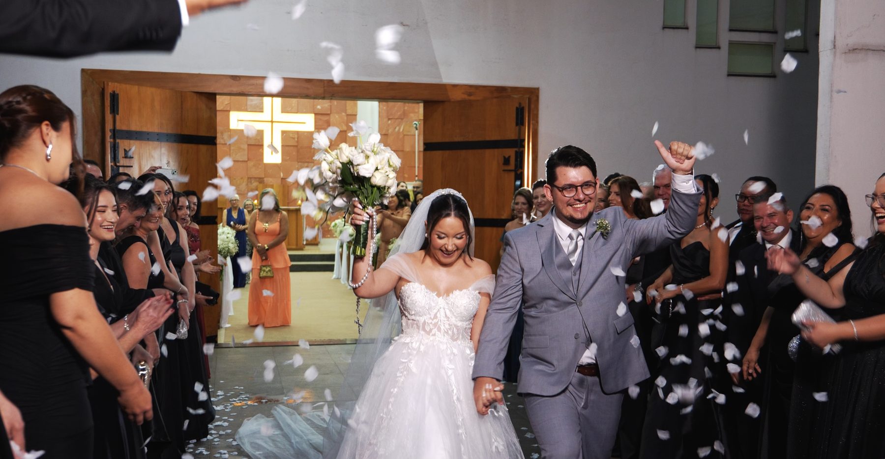 Noivos saindo da igreja sob uma chuva de pétalas